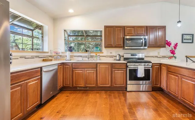 a kitchen with stainless steel appliances a stove sink microwave refrigerator and cabinets