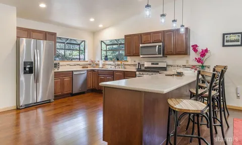 a kitchen with kitchen island granite countertop wooden floors and stainless steel appliances