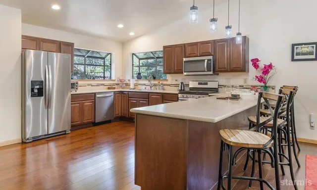 a kitchen with kitchen island granite countertop wooden floors and stainless steel appliances