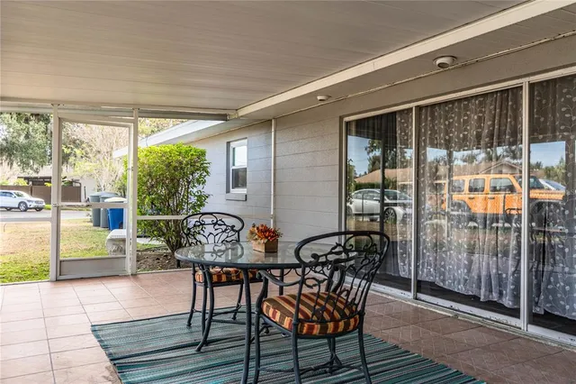 a view of a patio with table and chairs with wooden floor and floor to ceiling window