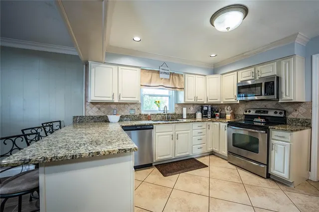 a kitchen with granite countertop a refrigerator and a stove top oven