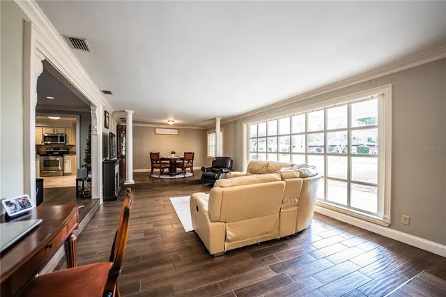 a living room with furniture kitchen view and a large window