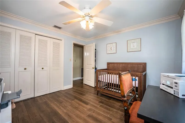 a bedroom with a bed a desk and chair with wooden floor