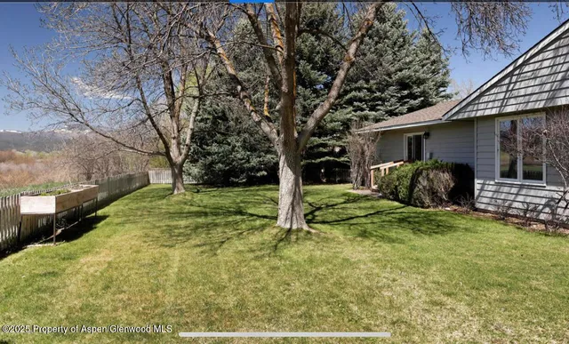 a view of a house with backyard and trees