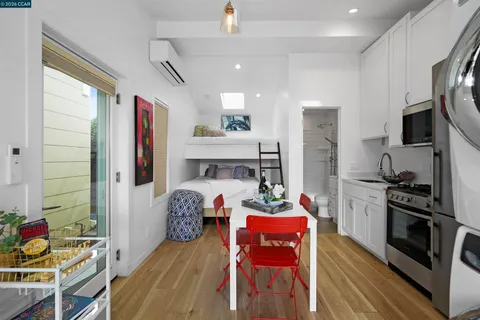 a kitchen with stainless steel appliances kitchen island granite countertop a refrigerator a stove top oven a dining table and chairs with wooden floor