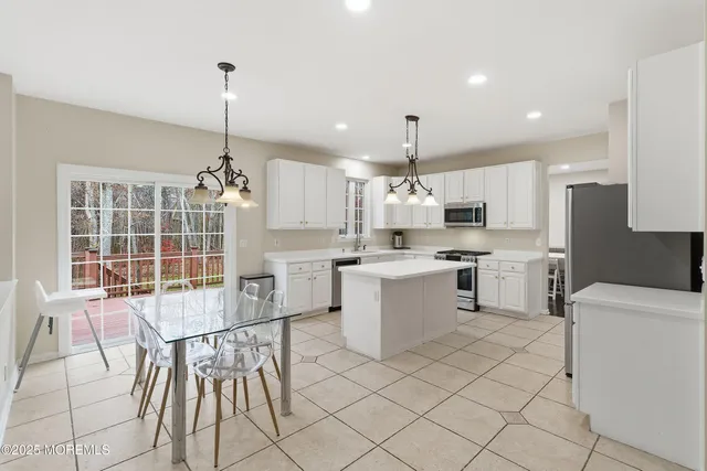 a open kitchen with white cabinets a sink dining table and chairs