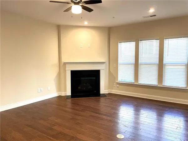 an empty room with wooden floor a fireplace and a large window