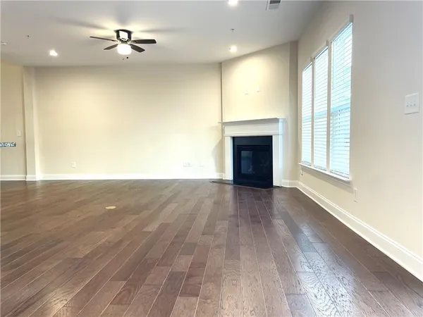 an empty room with wooden floor fireplace and windows
