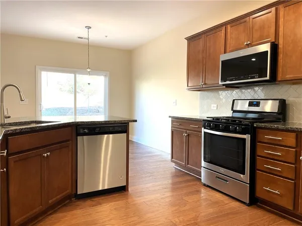 a kitchen with stainless steel appliances granite countertop a stove a sink and a microwave
