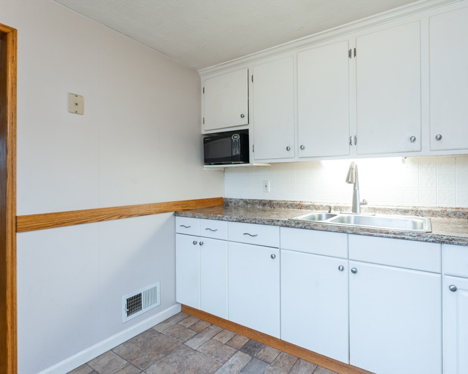 11 Colonial Road Woburn, MA 01801 - Photo 4 of 39 a kitchen with granite countertop white cabinets and white appliances