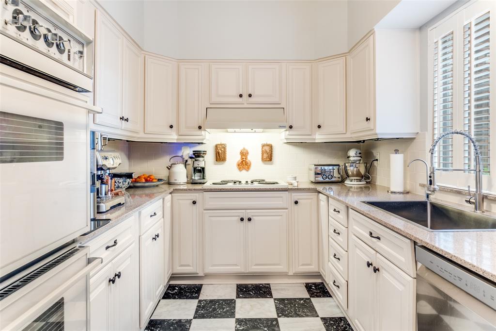 6306 Bandera Avenue, Unit B Dallas, TX 75225 - Photo 7 of 14 U-shaped kitchen featuring white cabinetry, granite countertops, and a black and white checkered tile floor