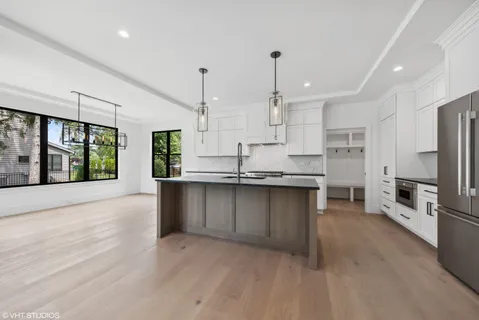 a kitchen with stainless steel appliances granite countertop a refrigerator a sink a stove and a wooden floors