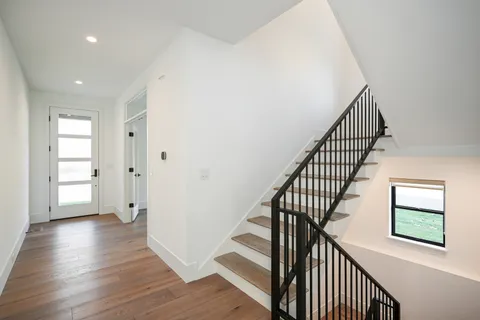 a view of a hallway with wooden floor and stairs