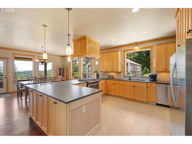 a kitchen with kitchen island granite countertop a sink a counter top space a large window and stainless steel appliances