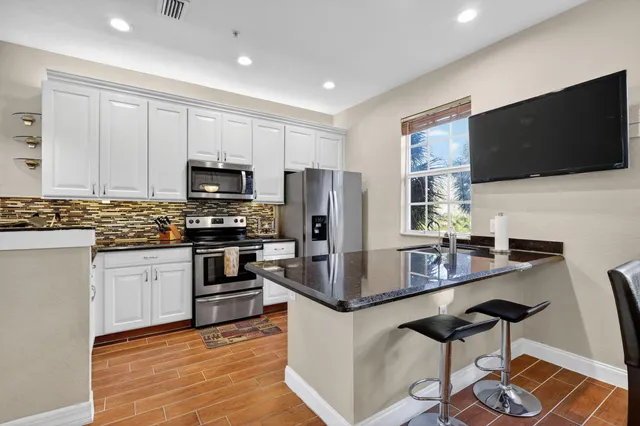 a kitchen with stainless steel appliances granite countertop a stove top oven a sink and a microwave