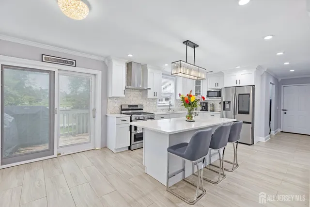 a kitchen with stainless steel appliances a dining table chairs stove refrigerator and cabinets