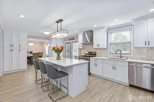a kitchen with granite countertop white cabinets stainless steel appliances dining table and chairs