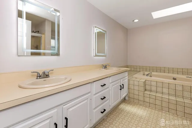 a bathroom with a double vanity sink mirror and bathtub