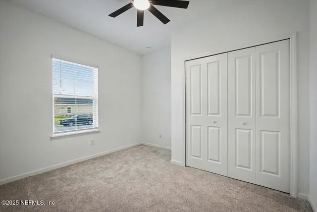 en empty room with windows and ceiling fan