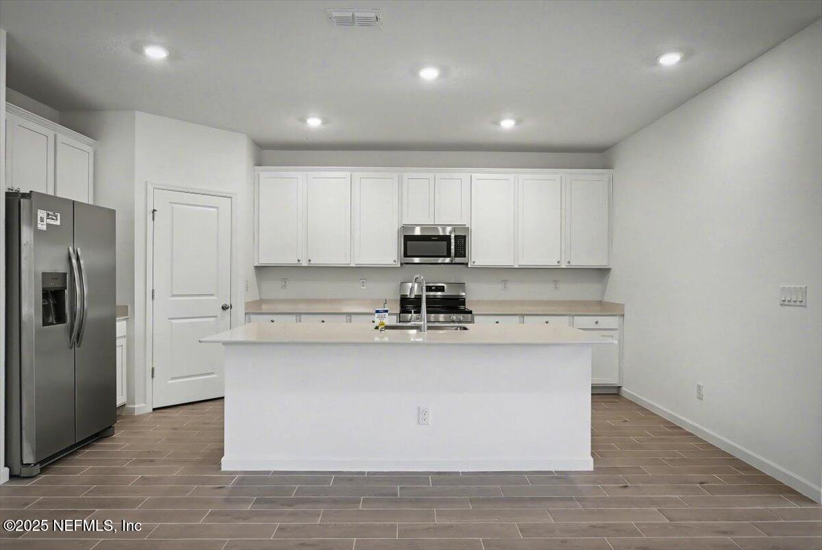 2692 Field Daisy Ln Green Cove Springs Green Cove Springs, FL 32043 - Photo 9 of 37 a kitchen with stainless steel appliances granite countertop a stove a sink a refrigerator and white cabinets with wooden floor