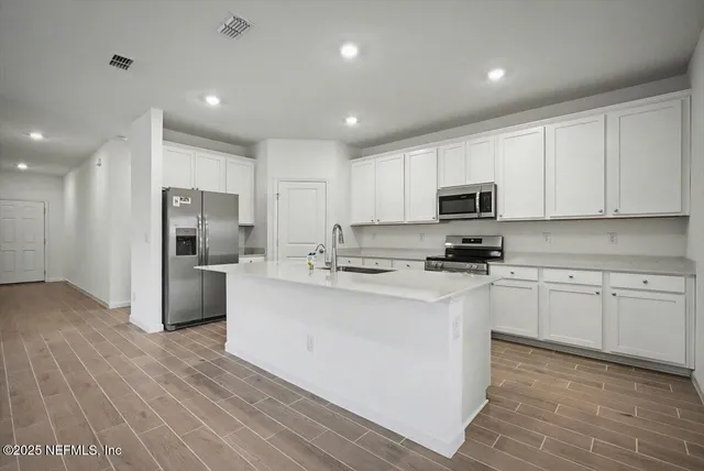 a kitchen with white cabinets and stainless steel appliances