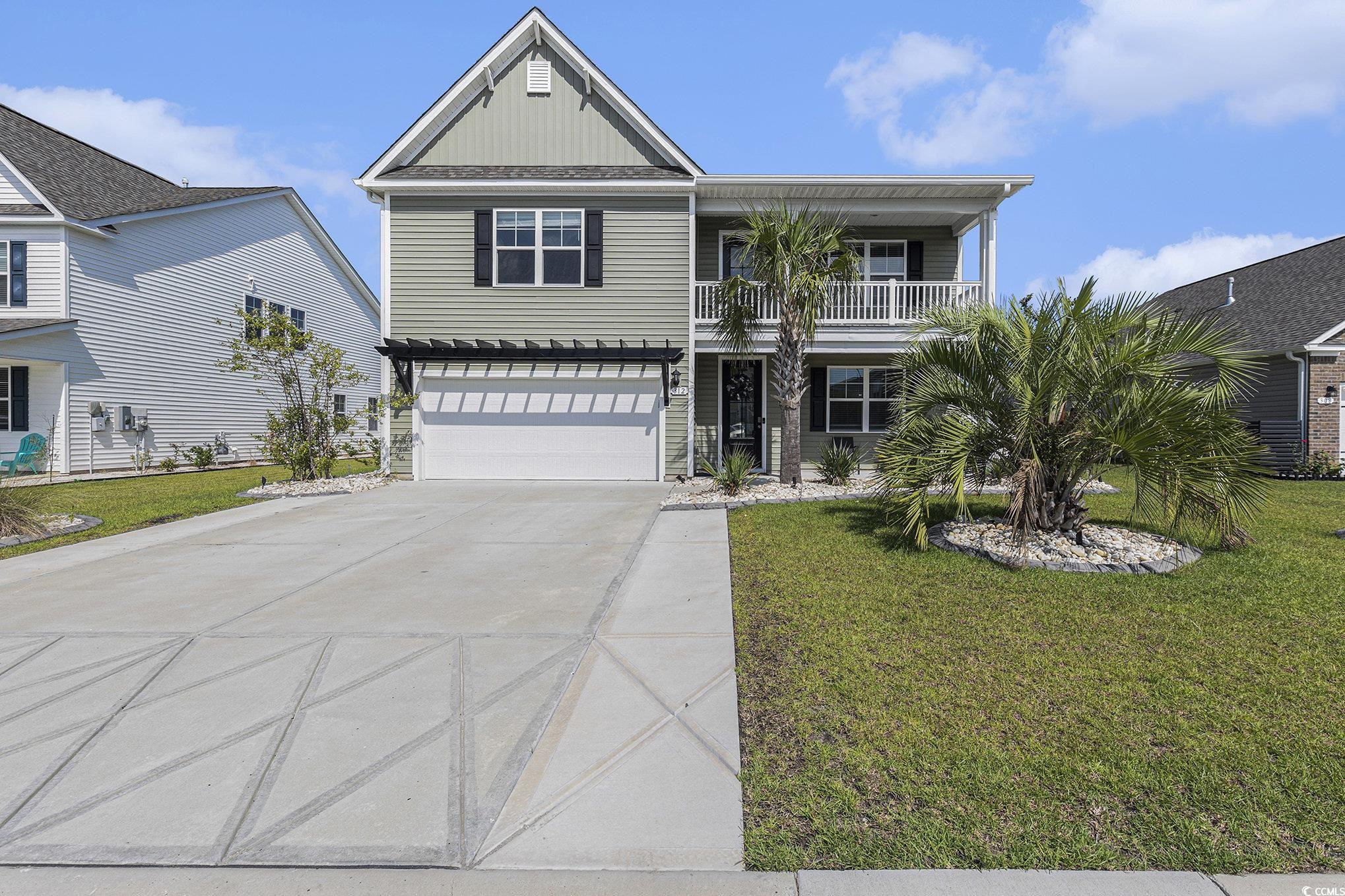312 Cattle Drive Circle Myrtle Beach, SC 29588 - Photo 1 of 34 View of front facade featuring a balcony, concrete driveway, an attached garage, and a front yard