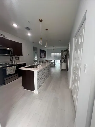 a kitchen with stainless steel appliances kitchen island granite countertop a stove top oven a sink a counter top space and cabinets