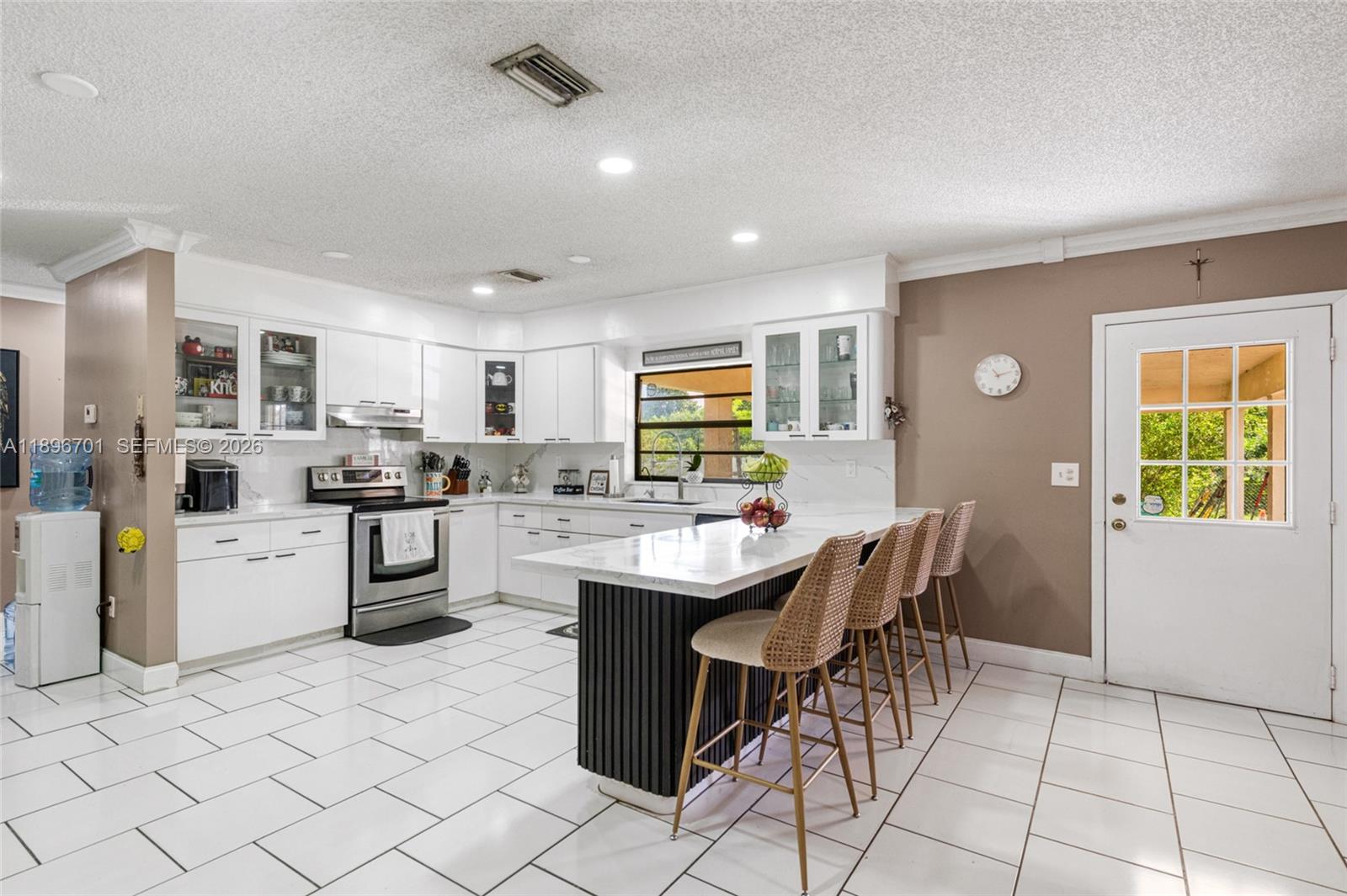 19491 Southwest 216th Street Miami, FL 33187 - Photo 13 of 32 a kitchen with stainless steel appliances kitchen island granite countertop a sink a stove a refrigerator a microwave oven with white cabinets and wooden floor