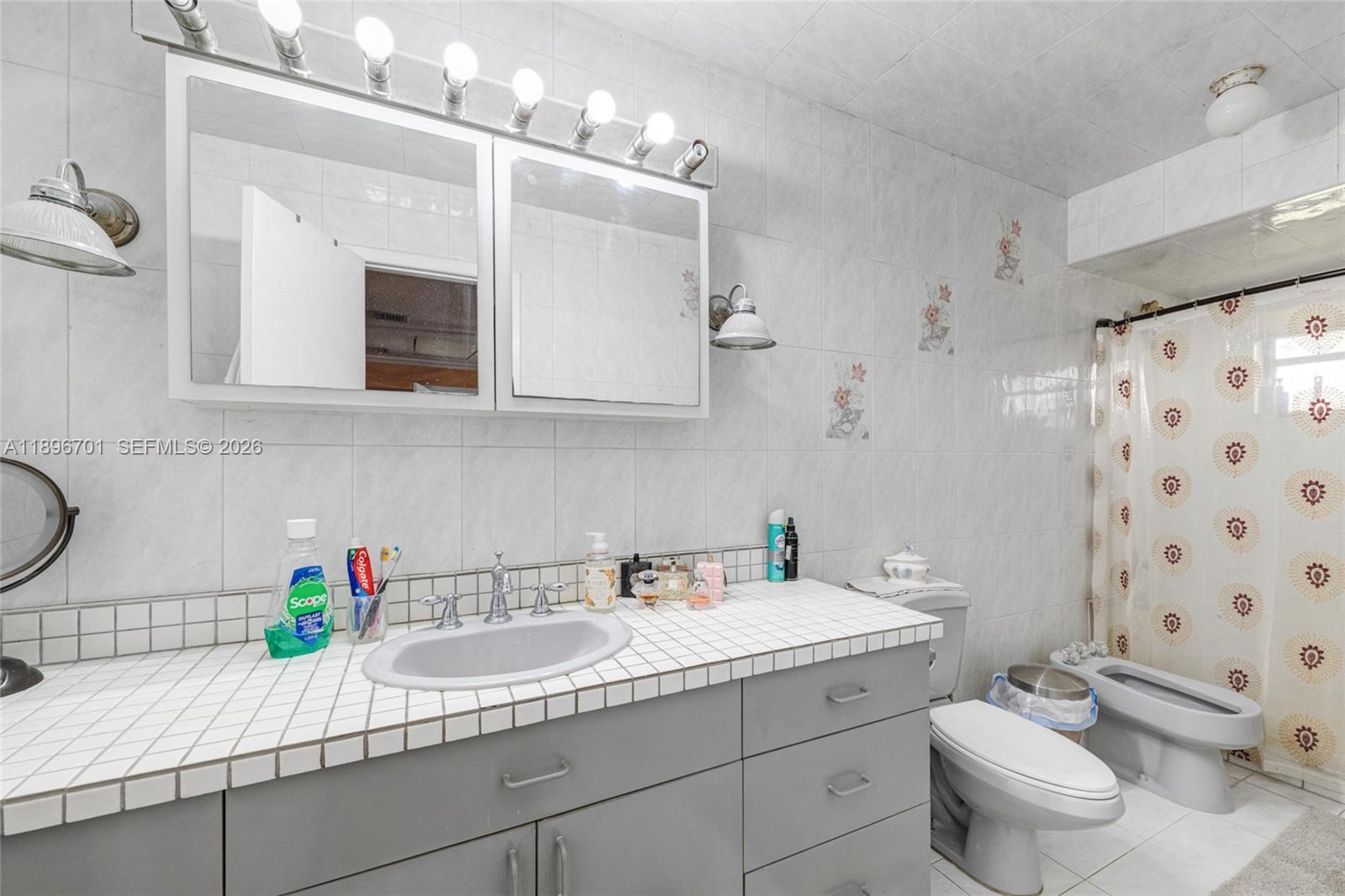 19491 Southwest 216th Street Miami, FL 33187 - Photo 21 of 32 a bathroom with a granite countertop toilet sink and mirror