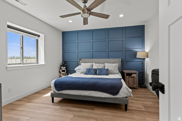 3111 South 1250 West Logan, UT 84321 - Photo 32 of 51 Room featuring a striking blue accent wall with panel molding, light wood-finish flooring, and a ceiling fan with integrated lighting