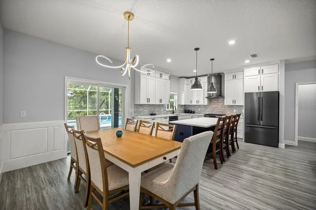 a dining room with stainless steel appliances kitchen island granite countertop a dining table chairs and refrigerator
