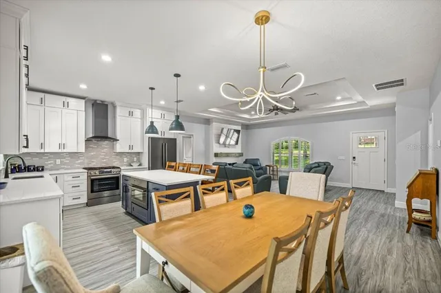 a view of a dining room and livingroom with furniture wooden floor a chandelier