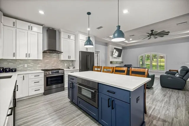 a large kitchen with stainless steel appliances a stove center island a oven a counter space and a window