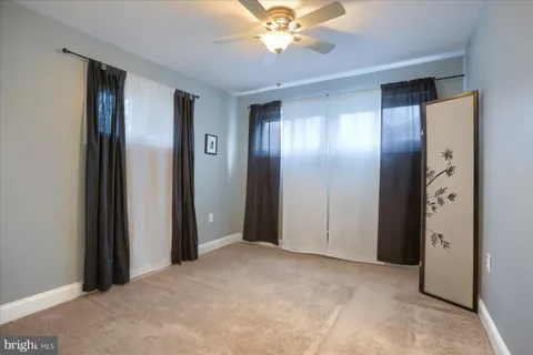 a view of a hallway with a chandelier fan and a bathroom