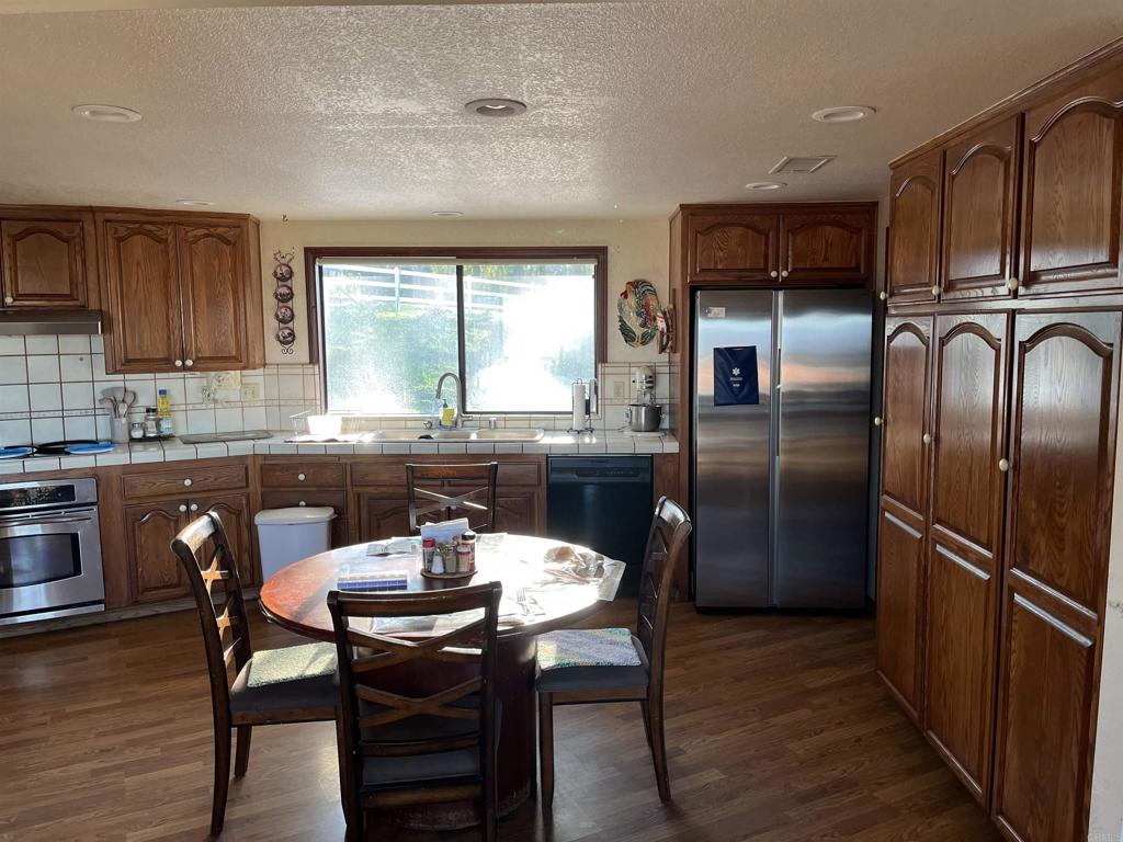 17910 Bluegrass Road Ramona, CA 92065 - Photo 25 of 33 a kitchen with stainless steel appliances granite countertop a dining table chairs refrigerator and sink
