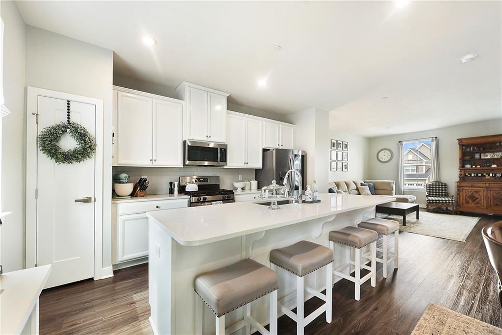 4302 Spruce Road Gibsonia, PA 15044 - Photo 6 of 24 a kitchen with stainless steel appliances granite countertop a stove top oven a refrigerator a sink dishwasher a dining table and chairs with wooden floor