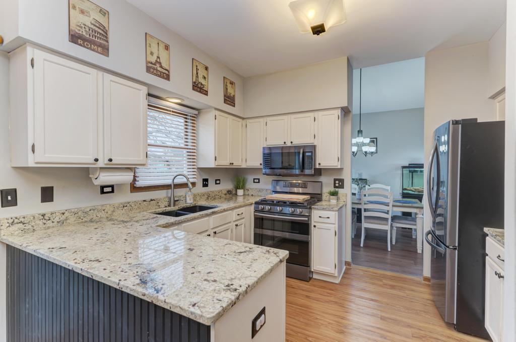 460 Springwood Lane Bolingbrook, IL 60440 - Photo 11 of 35 a kitchen with a refrigerator a stove a sink dishwasher and wooden cabinets with wooden floor
