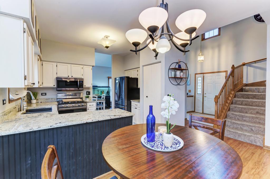460 Springwood Lane Bolingbrook, IL 60440 - Photo 15 of 35 a kitchen with stainless steel appliances granite countertop a table chairs and couches