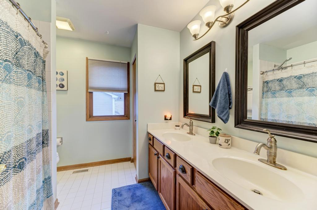 460 Springwood Lane Bolingbrook, IL 60440 - Photo 23 of 35 a bathroom with a double vanity sink a mirror and a bathtub