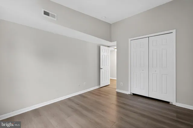 a view of an empty room with wooden floor and closet area