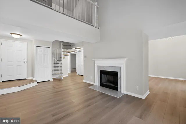 a view of an empty room with wooden floor fireplace and a window