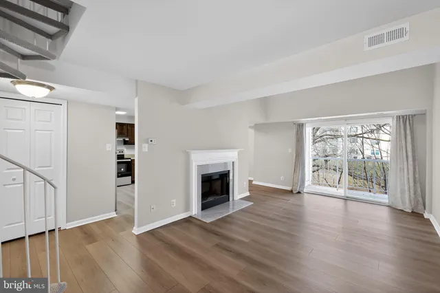an empty room with wooden floor fireplace and windows