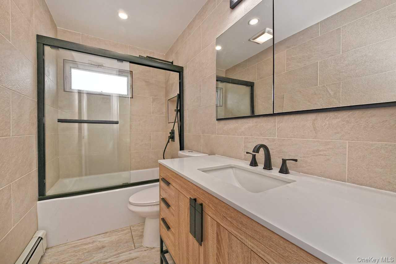 107 Beverly Road Massapequa, NY 11758 - Photo 19 of 41 a bathroom with a sink a toilet and shower