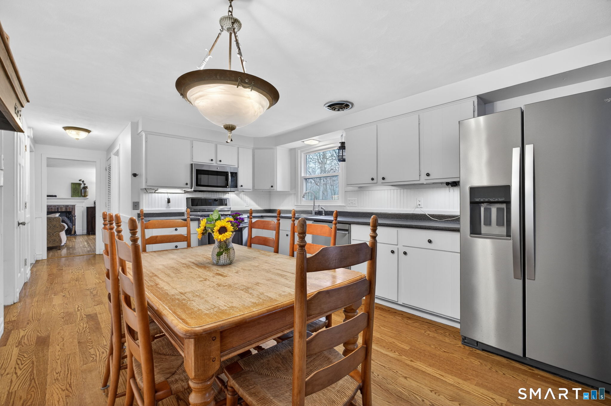 185 Ingham Hill Road Old Saybrook, CT 06475 - Photo 18 of 46 a kitchen with stainless steel appliances granite countertop a stove a refrigerator a sink a dining table and chairs with wooden floor