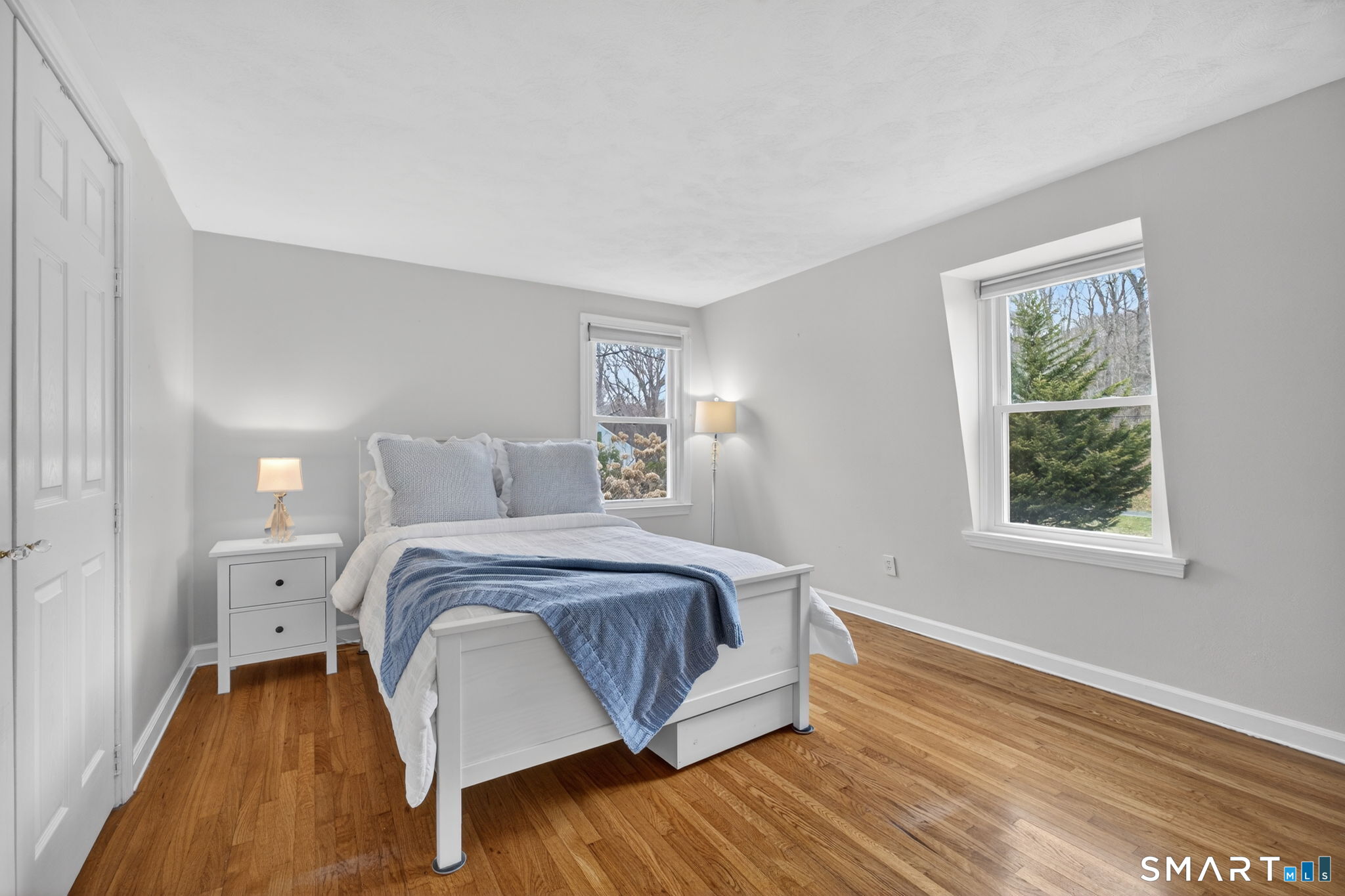 185 Ingham Hill Road Old Saybrook, CT 06475 - Photo 35 of 46 a bedroom with a bed lamp and a large window with wooden floor