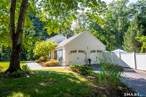 a view of a house with a yard plants and large tree