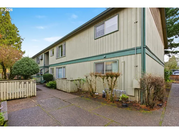 a view of a white house with a big yard and potted plants
