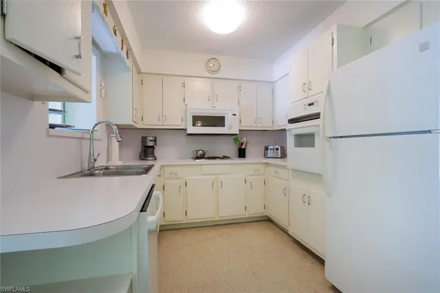 a kitchen with white cabinets and white appliances