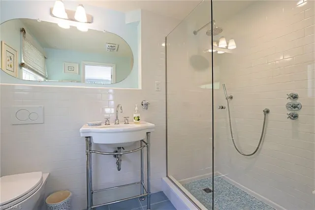 a bathroom with a shower a sink a toilet and mirror