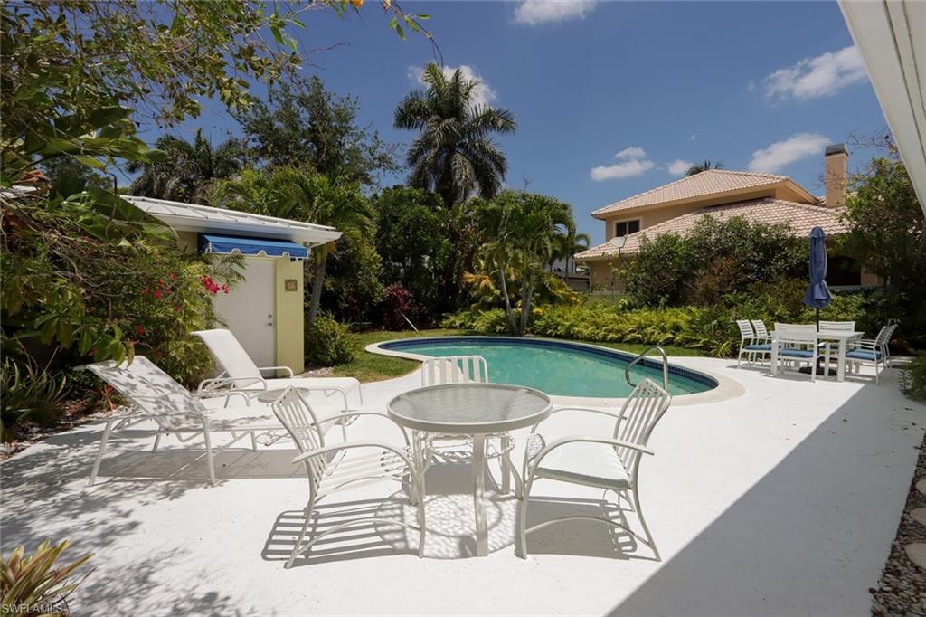 361 1st Avenue North Naples, FL 34102 - Photo 3 of 28 a view of a patio with a table and chairs potted plants and palm tree